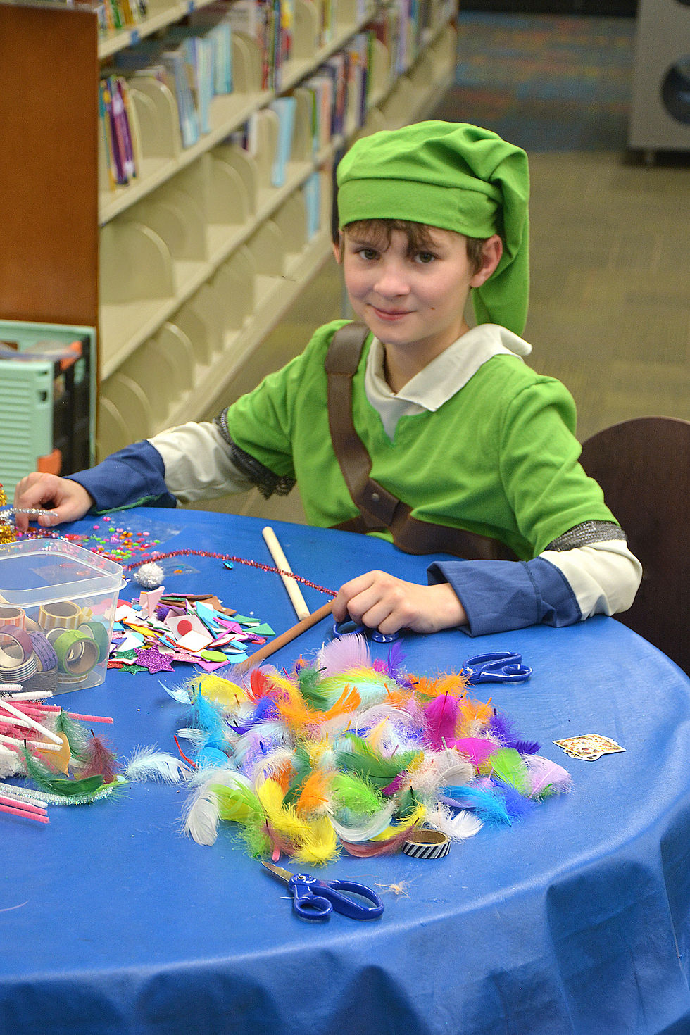 A child dressed as Link from Zelda sitting at a table in a library