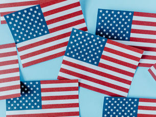 Small paper copies of the American Flag scattered across a blue background.