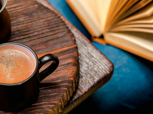 Photo - overhead shot of a ceramic mug with cocoa in it next to an open hardback book