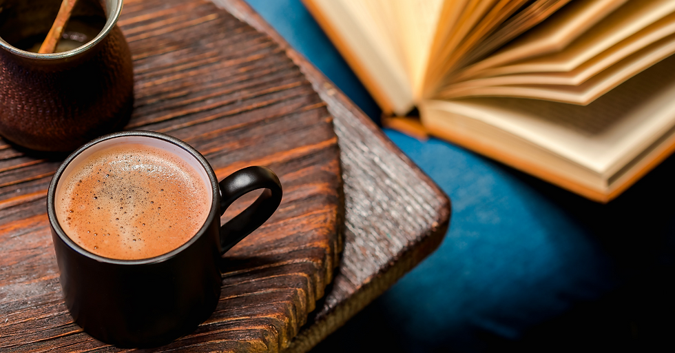 Photo - overhead shot of a ceramic mug with cocoa in it next to an open hardback book