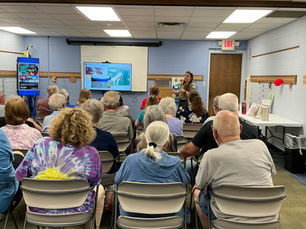 Older adults attend a ranger talk in a community room, watching slides labeled Changes in the Valley under an EXIT sign.