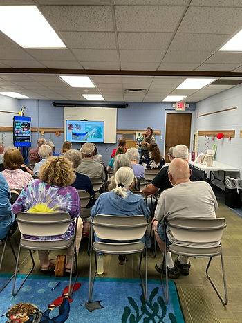 Older adults attend a ranger talk in a community room, watching slides labeled Changes in the Valley under an EXIT sign.