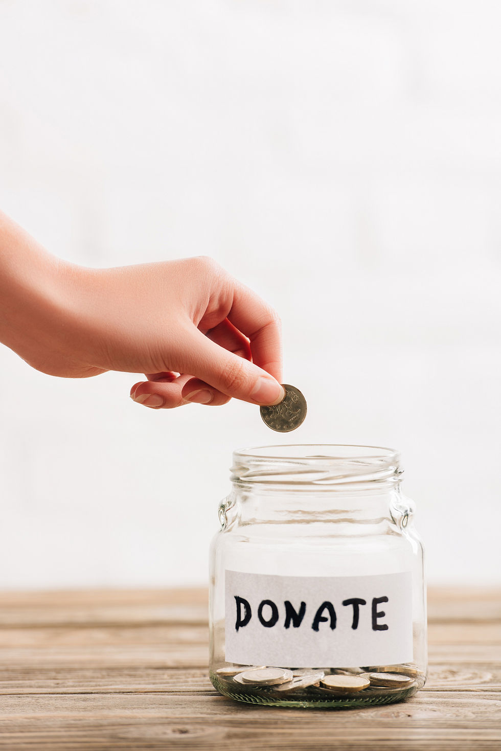 hand dropping a coin into a jar labeled "Donate".
