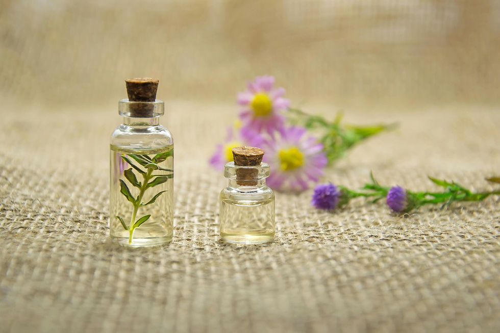 Small glass bottles and sprigs of herbs sitting on a white table.