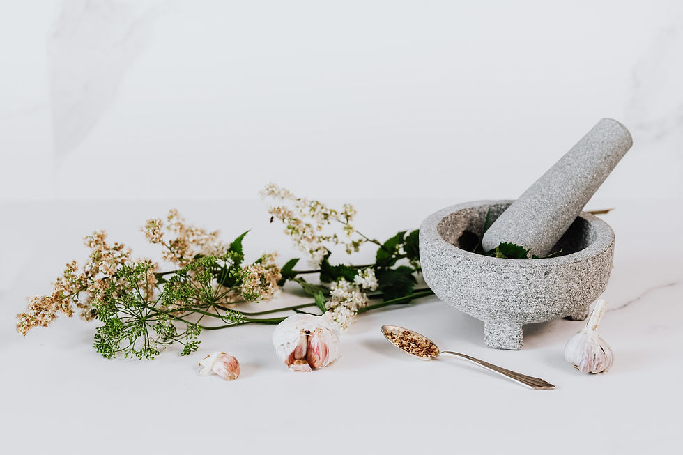 Mortar and pestle sitting on a table with a variety of herbs